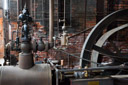 Another view of the staeam engine. The fire boxes are in the background with the boilers above. The governor is in the foreground left and the flywheel and belt wheel are foreground right.