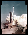 A Gemini lift-off.  Note that for the Titan/Gemini launch vehicles that the service tower is just laid down. The rocket was 109 feet tall so that is about the height of a twelve story build lying on the ground there. It is raised and lowered hydralically. Probably GT-3 Grissom and Young