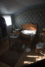 A hotel bedroom. Note the lady's boots at the foot of the bed. And the chamber pot back against the wall.