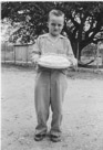 Aged 7 years.
May 19, 1949.
Child does not appear to be birthday happy. Cake also appears to be heavy.
At the Johnson Place. Note hammock in tree in the background. Tree is still there.