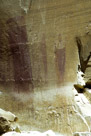 The left figure here is the right figure of the previous picture. There appears to be a possible snake figure between the left figure and the thin middle figure. The middle figure may have two 'feathers indicated and two legs. The tapered figure at the right appears to have two upraised arms with fingers indicated on the left one. The 'head' appears to have some internal structure and possible feed are indicated. The process of creating the large figure at the left appears to have created some runoff seen at the bottom of the figure.