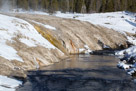 Runoff from geysers and hot springs run down the travertine bank of the Firehole river.