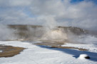 Castle geyser before an eruption. The cone is covered by steam.  There are a couple of hot springs adjacent to the cone. Water bubbles over the side of the cone from time to time between eruptions. Eruptions are around 7 hours apart.